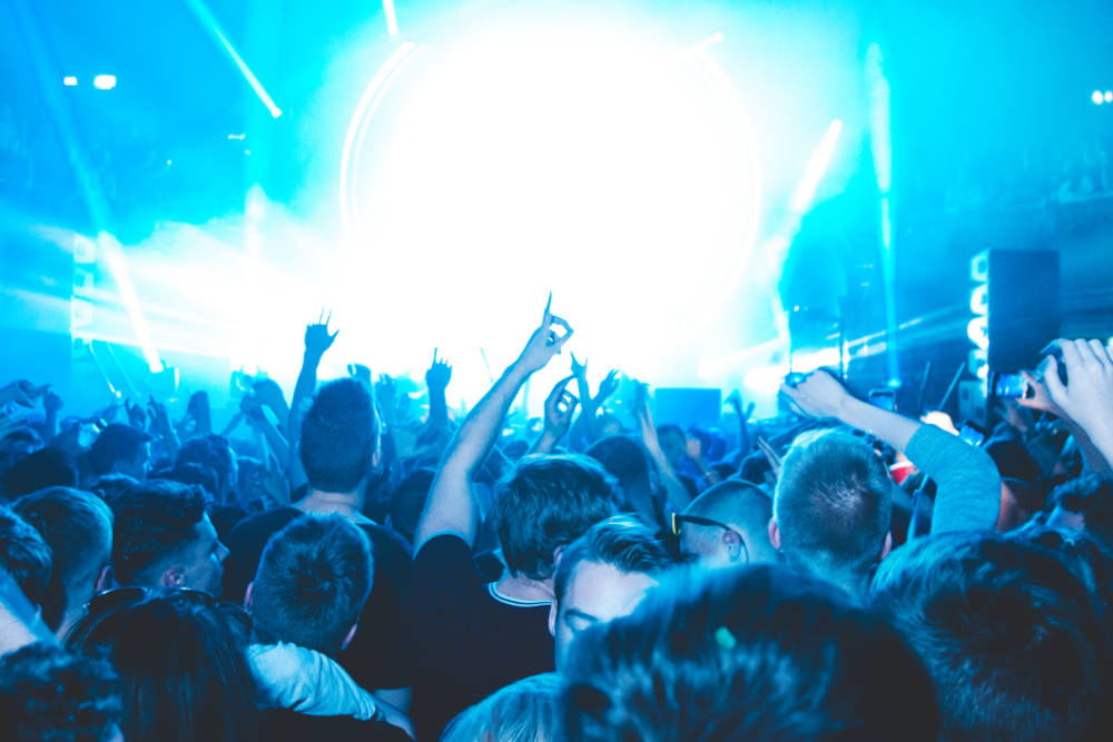 People at a concert facing the stage with various colours of paint powder in the air